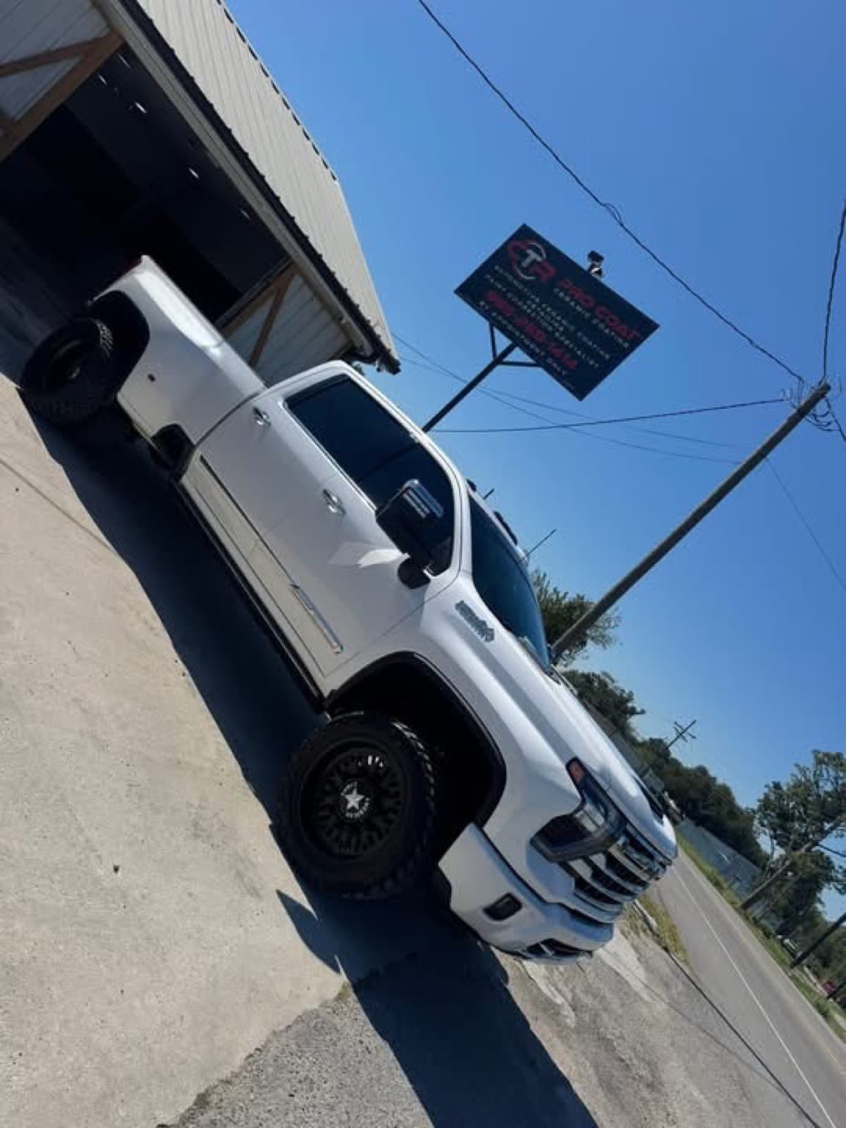 Ceramic-coated lifted white GMC Sierra in front of the CTR Pro Coat ceramic coating sign in Lockport, LA