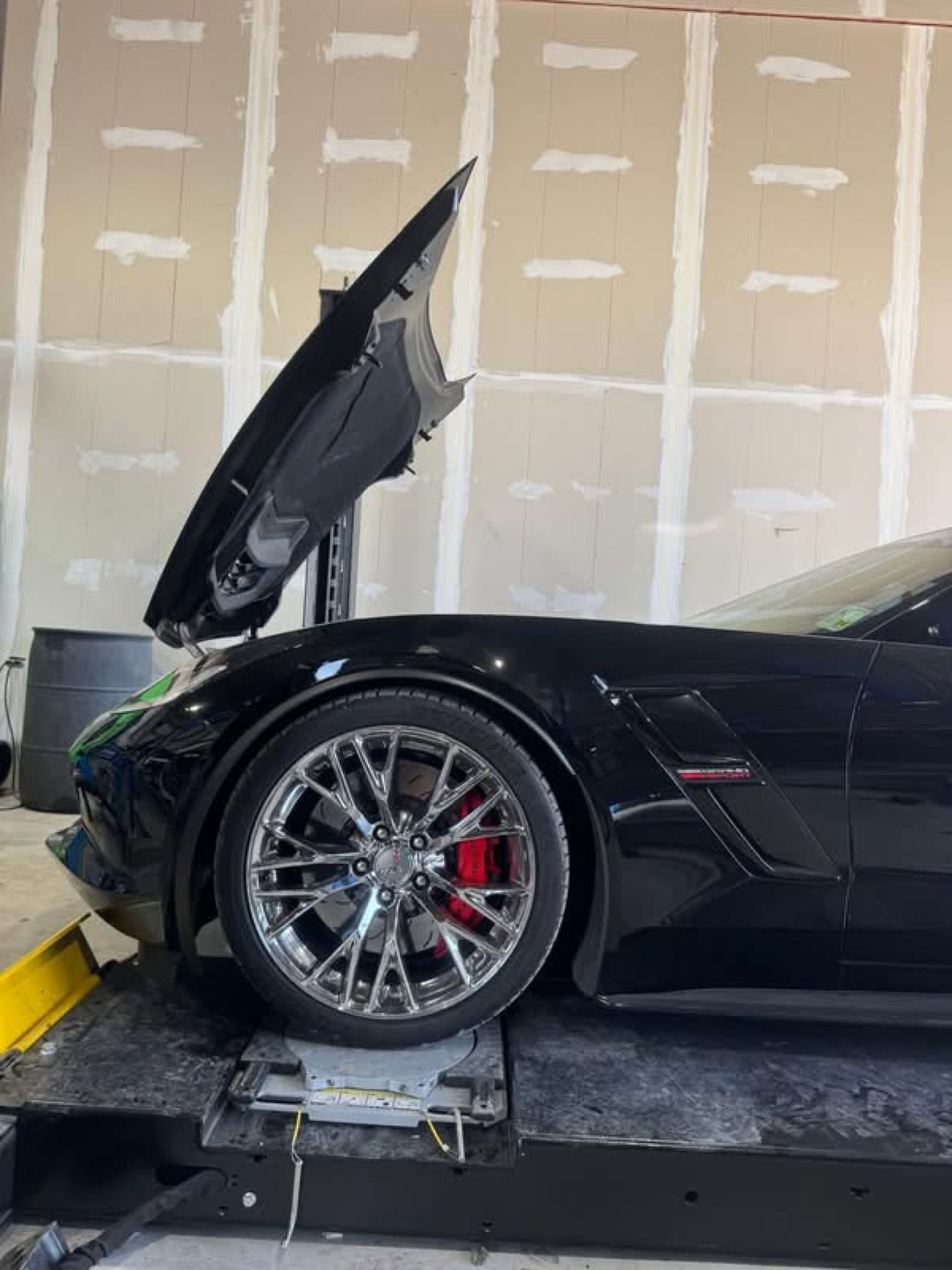 Black Chevrolet Corvette Z06 with hood up for performance work at Elite Custom Automotive in Lockport, LA