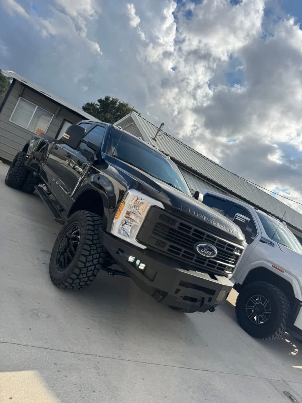 Lifted black Ford F-250 Super Duty with custom bumper and mud-terrain tires by Elite Custom Automotive in Lockport, LA