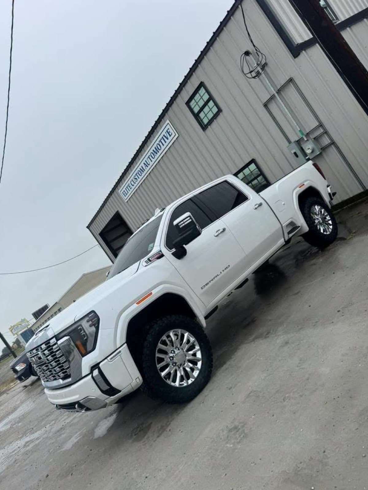 Lifted white GMC Sierra Denali HD outside the Elite Custom Automotive building in Lockport, LA