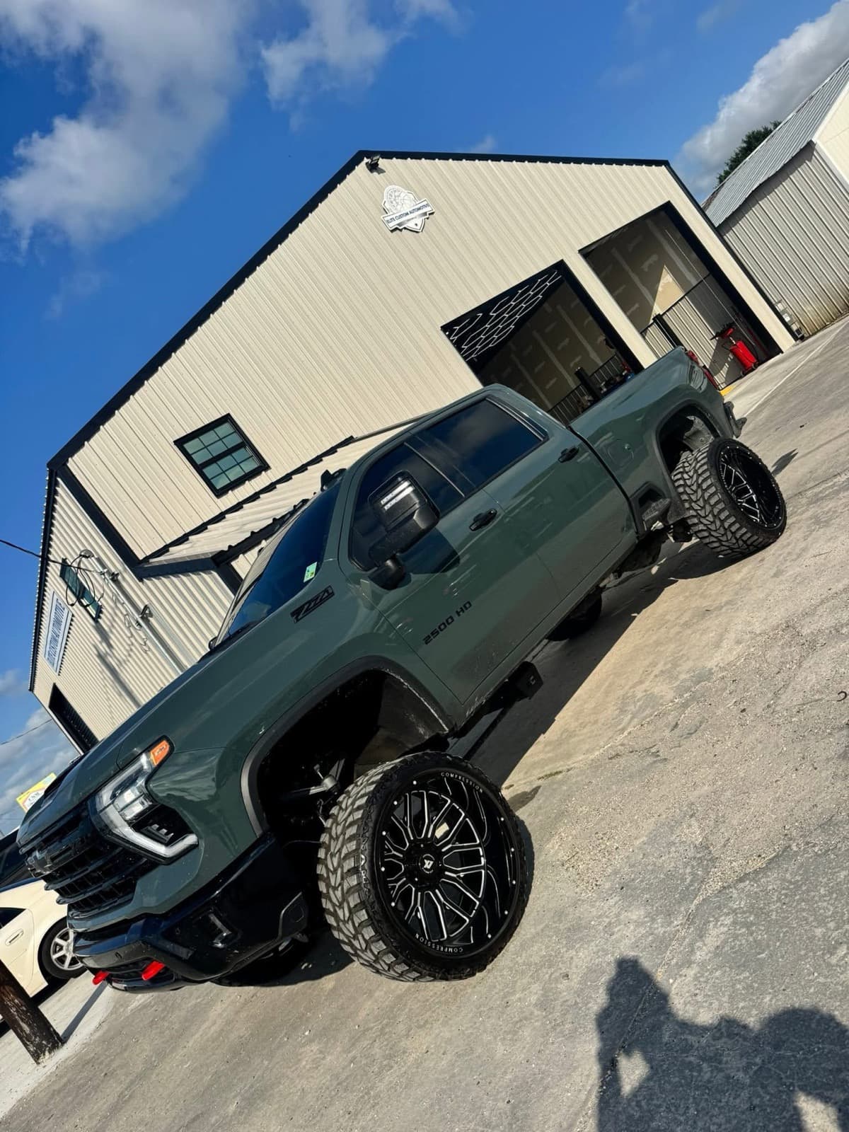 Lifted dark green Chevrolet Silverado 2500HD Z71 on custom black wheels outside the Elite Custom Automotive shop in Lockport, LA