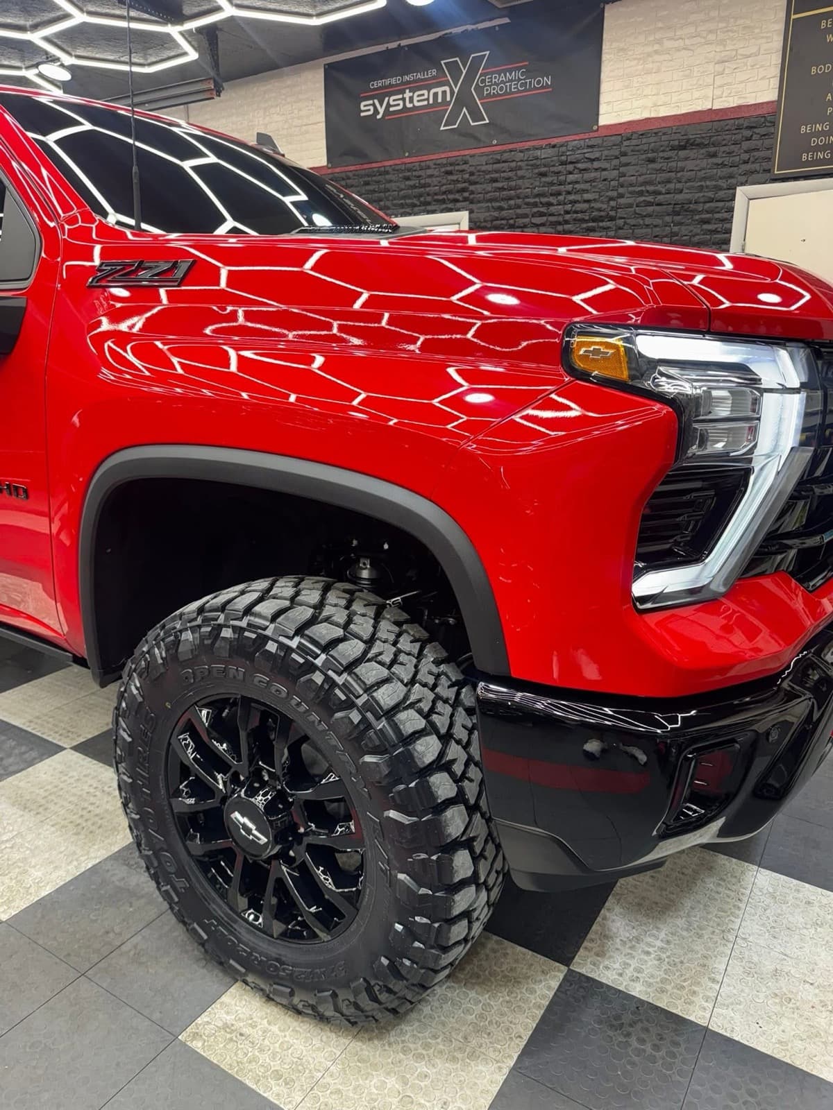 Ceramic-coated red Chevrolet Silverado 2500HD Z71 inside the hexagon-lit Elite Custom Automotive shop in Lockport, LA