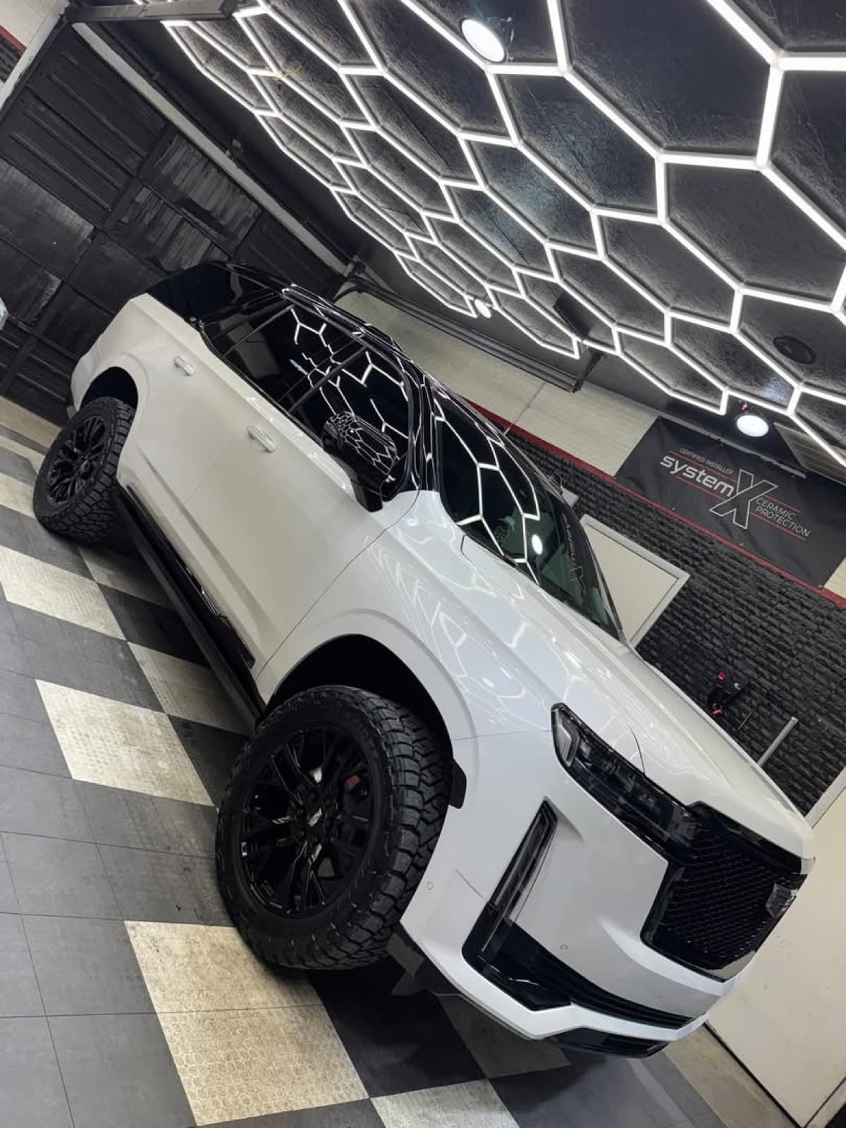 White Cadillac Escalade on custom black wheels inside the Elite Custom Automotive hexagon-lit shop in Lockport, LA