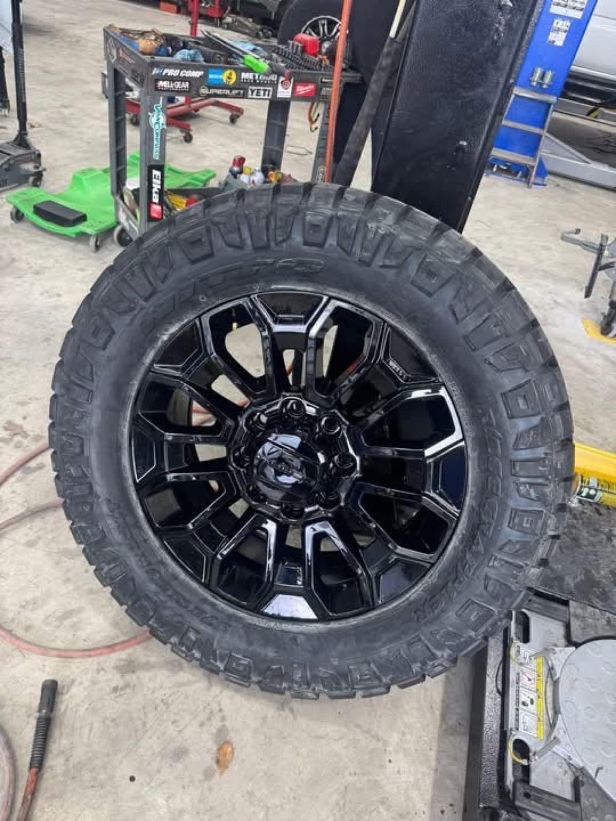 Custom black multi-spoke wheel mounted on a Nitto mud-terrain tire at Elite Custom Automotive in Lockport, LA