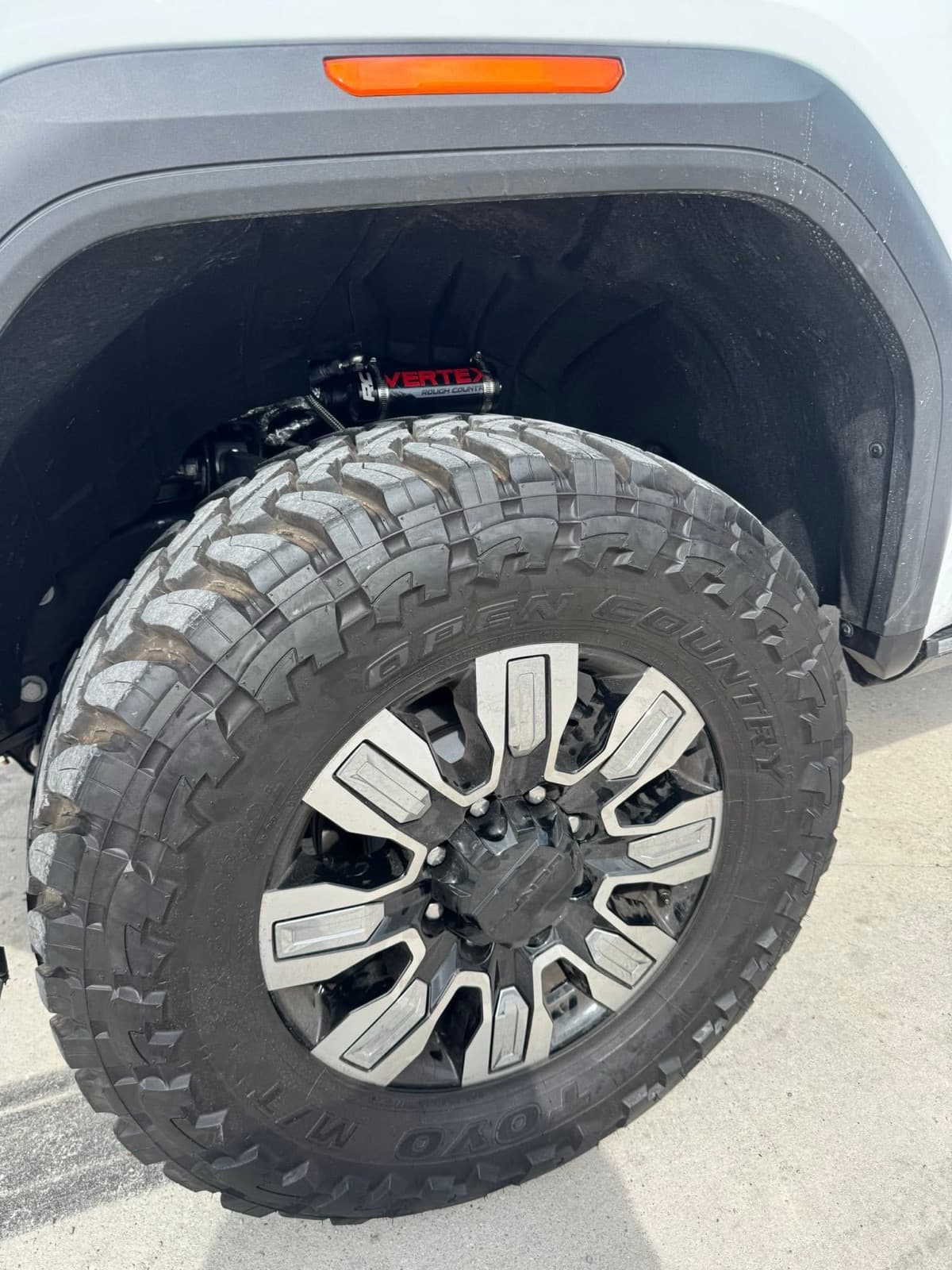 Silver and black multi-spoke wheel with Toyo Open Country mud-terrain tire installed at Elite Custom Automotive in Lockport, LA